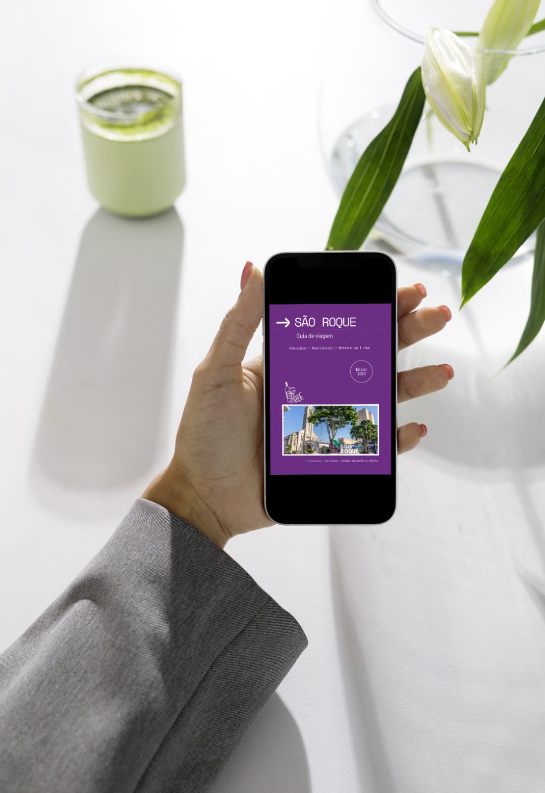 Mão segurando celular com o Guia Exploralia